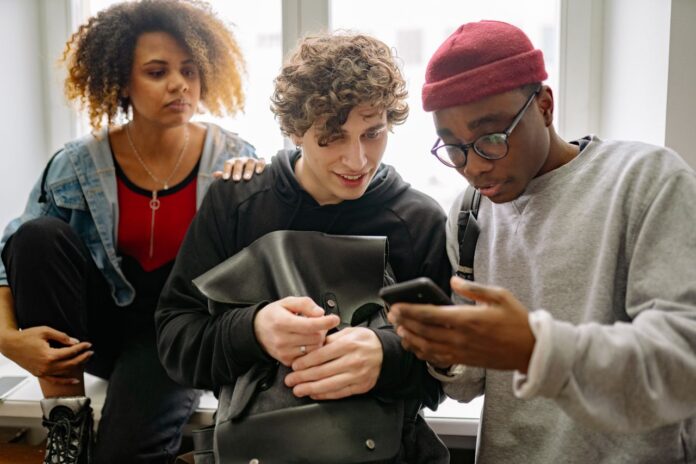 A diverse group of young friends interacting with a cellphone indoors