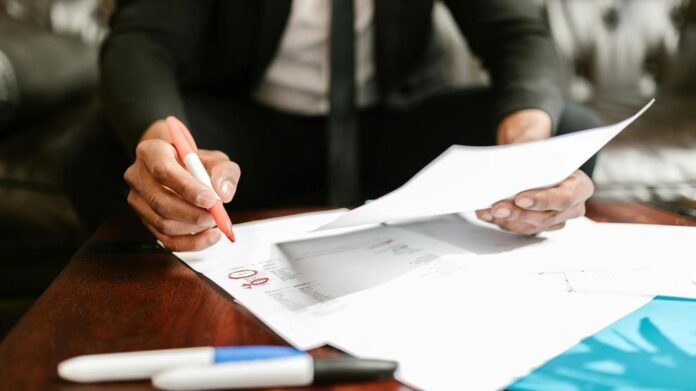 A professional in business attire reviews financial documents. Photo: RDNE Stock project / Pexels