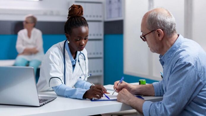 A doctor reviews paperwork with a senior male patient in an office. Photo: DC Studio / Freepik