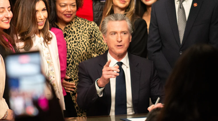 Legislators surround California Gov. Gavin Newsom Wednesday as he signs a bill giving $90 million to Planned Parenthood, Feb. 11, 2026. Photo: Madeline Shannon / The Center Square.